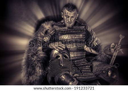 Portrait of a courageous ancient warrior in armor with sword and shield. Black-and-white photo.