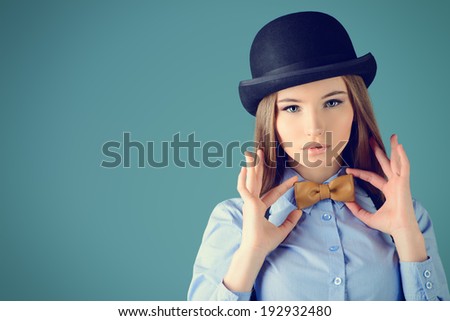 Elegant girl model poses in blouse, bow tie and bowler hat. Refined style of old Europe.