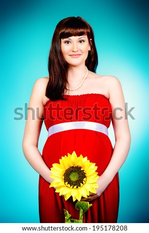 Portrait of a beautiful pregnant woman with sunflower. Pregnancy. Healthcare. Studio shot.