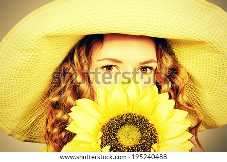 Close-up portrait of a beautiful red-haired girl with sunflower smiling at camera. Summer. Studio shot.