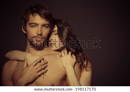 Beautiful passionate naked couple in love. Over black background.