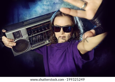 Portrait of a modern girl with tape recorder over grunge background. Street urban style.