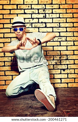 Trendy dancer dancing hip-hop against brick wall.