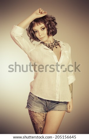 Sexual girl alluring in denim shorts and white shirt. Beauty, fashion. Sepia.