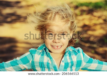 Portrait of a sly little girl in the countryside. Happy childhood. Emotions.