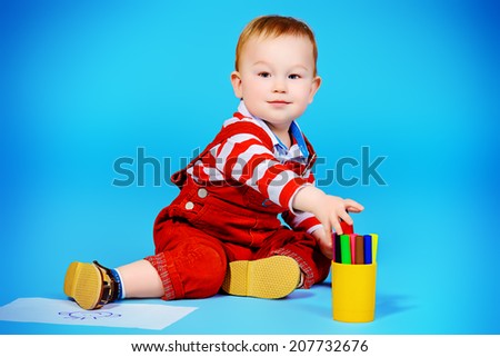 Cute baby boy playing with felt pens on a floor. Childhood.