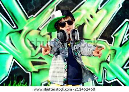 Trendy 7 year old boy on the street. Graffiti background. Modern generation.