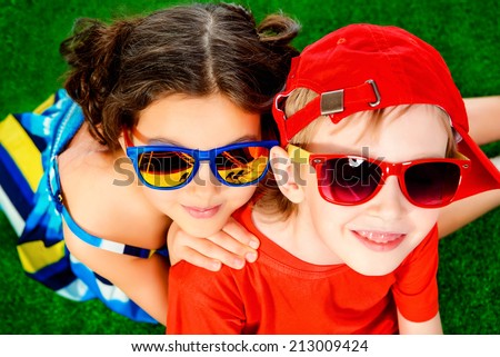 Happy smiling girl and boy in bright summer clothes lying on a grass. Children.