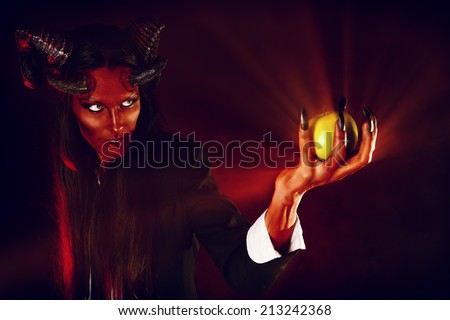 Portrait of a devil with horns holding apple. Devilish temptation. Fantasy. Art project.