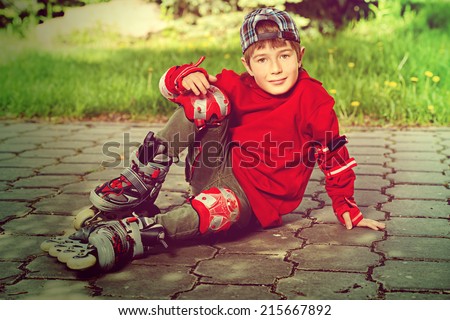 Cool 7 year old boy rollerblades on the street. Childhood. Summertime.