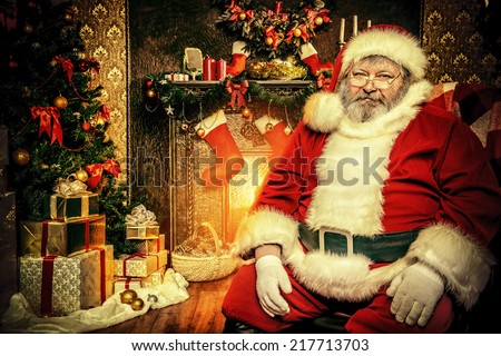 Tired Santa Claus sitting by the fireplace with a bag of gifts. Christmas home decoration.