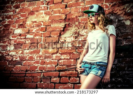 Beautiful modern girl near the brickwall. Youth style. Fashion shot.