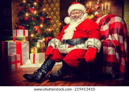 Santa Claus brought gifts for Christmas and sat down to rest by the fireplace. Home decoration.