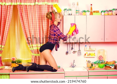 Pretty sexy pin-up girl cleans her glamorous pink kitchen. Retro style. Fashion.