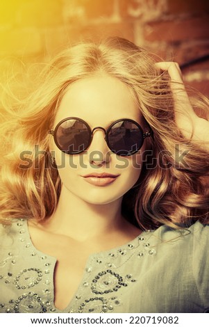 Lovely young woman in casual blouse and sunglasses outdoor. Fashion shot.