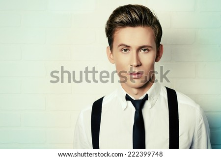 Portrait of a handsome young man in white shirt andblack tie by white brick wall. Business.