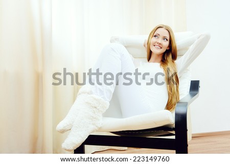Happy young woman resting at home in a comfortable chair.