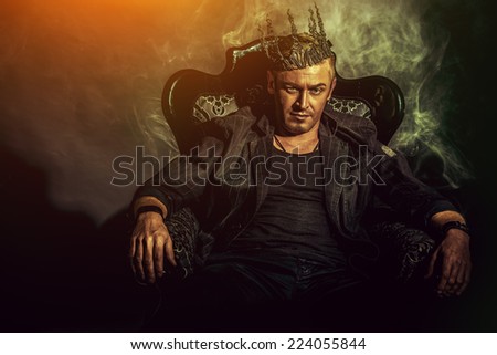 Portrait of a masculine handsome man in elegant black suit sitting in a chair in a classic vintage style.