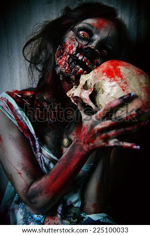 Frightening bloody zombie girl with a skull. Halloween.