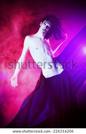Art photo of a beautiful graceful brunet man dancing with airy black chiffon. Fashion.