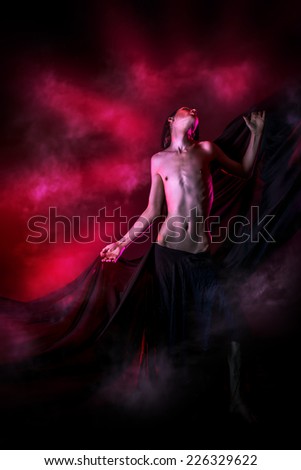 Art photo of a beautiful graceful brunet man dancing with airy black chiffon. Fashion.