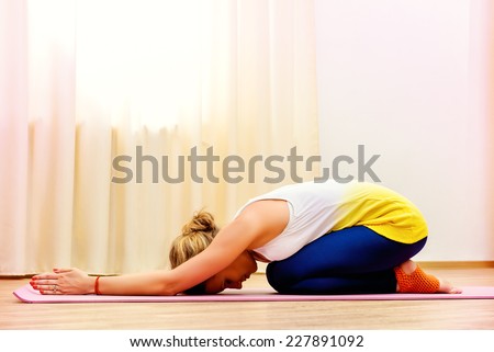 Slender athletic girl doing yoga exercises indoor. Professional trainer.
