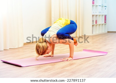 Slender athletic girl doing yoga exercises indoor. Professional trainer.