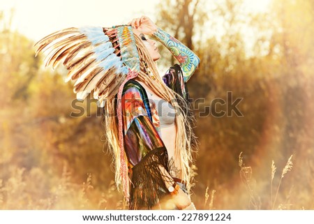 Close-up portrait of a beautiful girl wearing native american indian chief headdress. Western style. Jeans fashion.