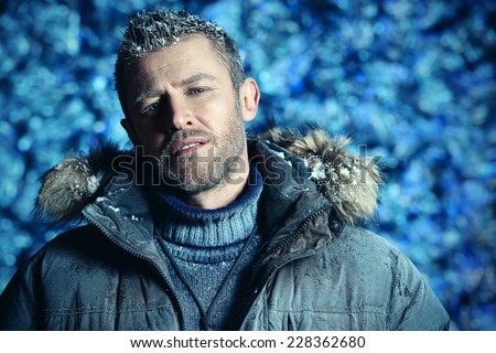 Portrait of a handsome brutal man dressed in winter clothes, covered with frost.