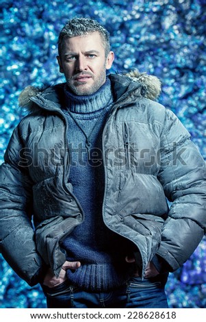 Portrait of a handsome brutal man dressed in winter clothes, covered with frost.