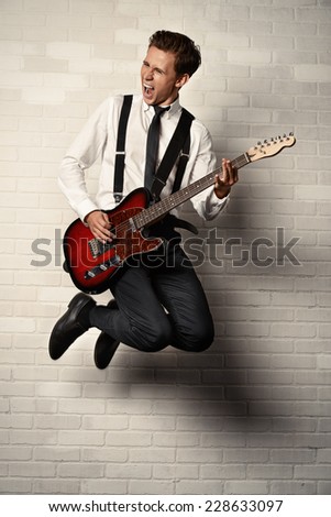 Expressive young man playing rock-n-roll music on his electric guitar. Retro, vintage style.
