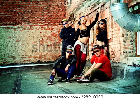 Group of young modern people posing together with fun. Urban lifestyle. Hip-hop generation.