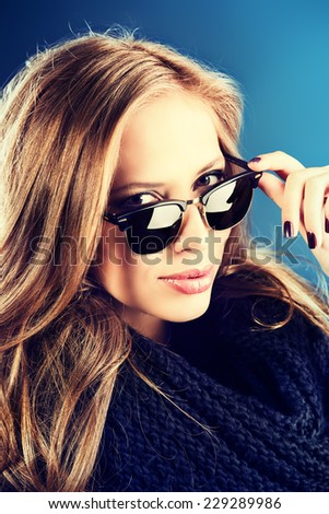 Close-up portrait of a smiling young lady with beautiful hair wearing black sunglasss.