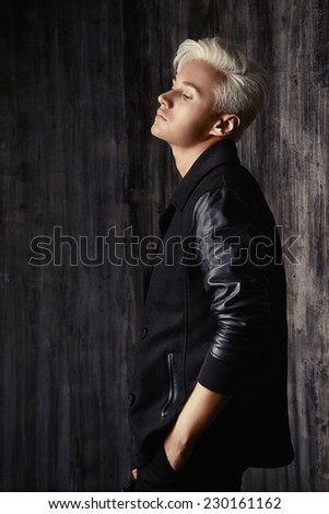 Portrait of a beautiful male model with blond hair wearing black jacket. Urban style. Fashion.