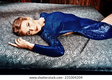 Beautiful sexy woman lying on the bed in the evening dress. Fashion. Interior.