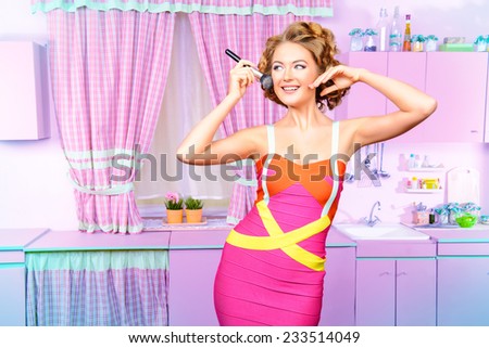 Pretty woman doing makeup on her glamorous pink kitchen at home. Beauty, fashion.