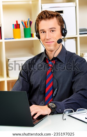 Friendly smiling young man customer service worker.  Call center male operator with phone headset working at the office.