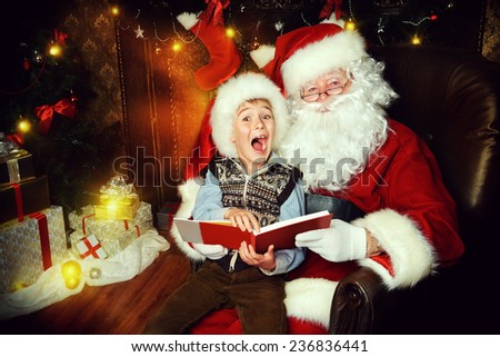 Santa Claus and happy boy sitting in Christmas room and reading a book. Christmas home decor.