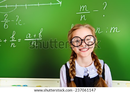 Smiling schoolgirl performs the task at the blackboard. Education.