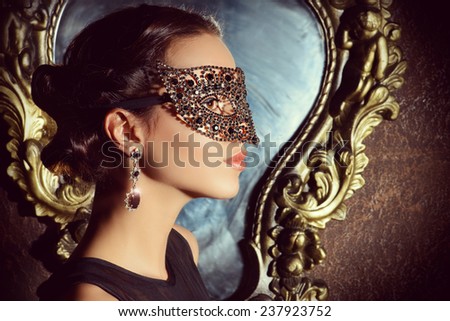 Close-up portrait of a beautiful woman in venetian mask. Carnival, masquerade. Jewellery, gems.