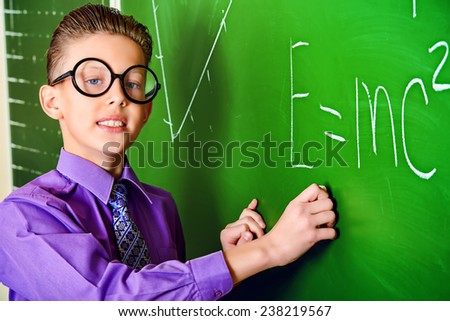 Smart schoolboy stands at the blackboard in the classroom. Education.