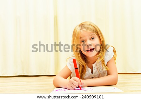 Cute girl on a floor and drawing on paper with colorful pens