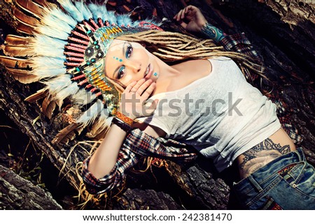 Close-up portrait of a beautiful girl wearing native american indian chief headdress. Western style. Jeans fashion.