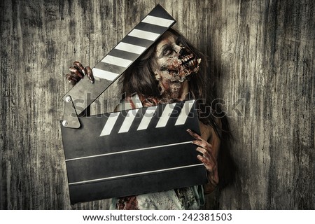 Filming a horror movie. Female zombie holding clapper board. Cinematography. Halloween.