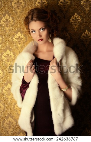 Elegant young woman in  evening dress and mink fur jacket posing in vintage interior. Jewellery.  Fashion shot.