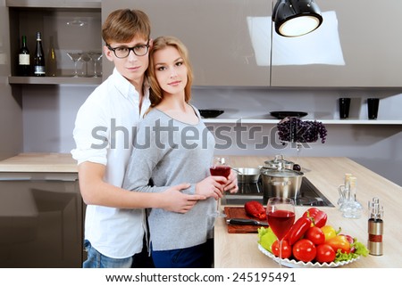 Happy young couple in love cooking a dinner on a kitchen and drink red wine. Healthy food. Happy family.