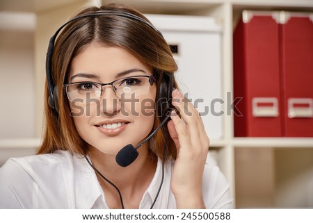 Friendly smiling young woman surrort phone operator at her workplace in the office. Headset. Customer service.