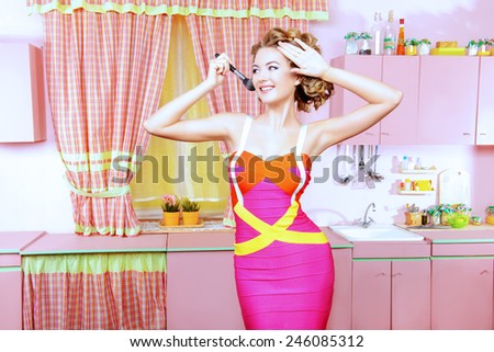 Pretty woman doing makeup on her glamorous pink kitchen at home. Beauty, fashion.