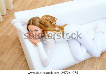 Happy young woman resting at home in a comfortable sofa.