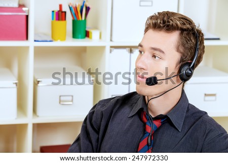 Friendly smiling young man customer service worker.  Call center male operator with phone headset working at the office.